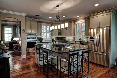 Example of a classic u-shaped medium tone wood floor eat-in kitchen design in Charleston with recessed-panel cabinets, stainless steel appliances, an island, gray backsplash and ceramic backsplash