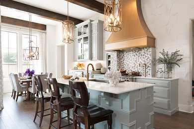 Inspiration for a mid-sized transitional l-shaped medium tone wood floor eat-in kitchen remodel in New Orleans with a farmhouse sink, multicolored backsplash, glass tile backsplash, stainless steel appliances, an island, raised-panel cabinets, blue cabinets and marble countertops