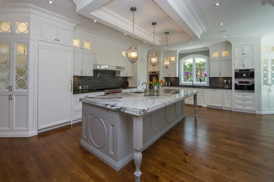 Example of a huge classic l-shaped medium tone wood floor and orange floor eat-in kitchen design in Toronto with an undermount sink, recessed-panel cabinets, white cabinets, granite countertops, black backsplash, ceramic backsplash, paneled appliances and an island
