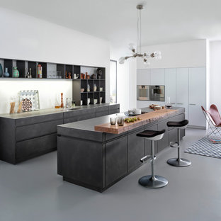 Esempio di una cucina minimalista di medie dimensioni con lavello sottopiano, ante lisce, ante grigie, top in cemento, paraspruzzi bianco, elettrodomestici in acciaio inossidabile, pavimento in cemento e isola