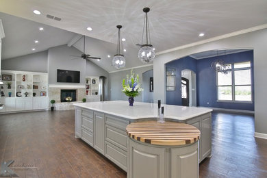 Large transitional l-shaped vinyl floor kitchen photo in Austin with a farmhouse sink, raised-panel cabinets, white cabinets, granite countertops, white backsplash, glass tile backsplash, stainless steel appliances and an island