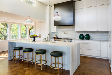 Moderne Küche mit Quarzit-Arbeitsplatte, Küchengeräten aus Edelstahl, braunem Holzboden, Kücheninsel, Unterbauwaschbecken, flächenbündigen Schrankfronten, weißen Schränken, Küchenrückwand in Grau und Rückwand aus Stein in Portland
