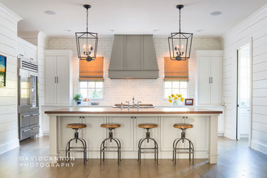 Photo of a rustic u-shaped kitchen in Atlanta with recessed-panel cabinets, white cabinets, marble worktops, white splashback, stainless steel appliances, medium hardwood flooring and an island.