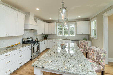 Modelo de cocina clásica renovada grande con salpicadero blanco, electrodomésticos de acero inoxidable, suelo de madera en tonos medios y una isla