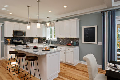 Example of a transitional light wood floor kitchen design in Boston with an undermount sink, shaker cabinets, white cabinets, granite countertops, multicolored backsplash, mosaic tile backsplash, stainless steel appliances and an island