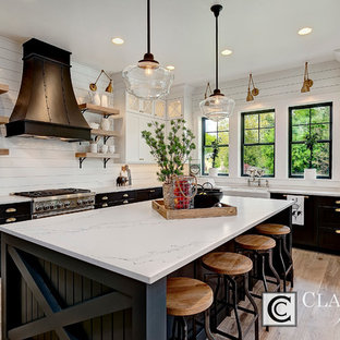 Large farmhouse open concept kitchen designs - Large farmhouse u-shaped light wood floor open concept kitchen photo in Boise with a farmhouse sink, shaker cabinets, white cabinets, quartz countertops, white backsplash, wood backsplash, stainless steel appliances and an island