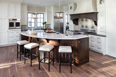 Example of a classic light wood floor kitchen design in Minneapolis with a farmhouse sink, shaker cabinets, white cabinets, multicolored backsplash, stainless steel appliances and an island