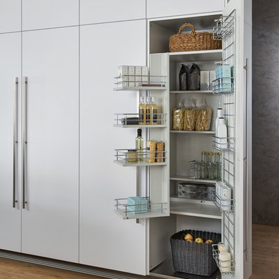 Example of a huge minimalist single-wall light wood floor eat-in kitchen design in New York with an undermount sink, flat-panel cabinets, solid surface countertops, black appliances, an island and white cabinets