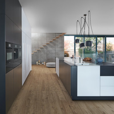 Example of a huge minimalist galley light wood floor eat-in kitchen design in New York with an undermount sink, flat-panel cabinets, black cabinets, solid surface countertops, black appliances and an island