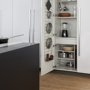 Idee per un'ampia cucina moderna con lavello sottopiano, ante lisce, ante nere, top in superficie solida, elettrodomestici neri, parquet chiaro e isola