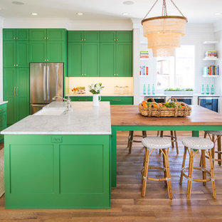Large beach style u-shaped eat-in kitchen in Minneapolis with a farmhouse sink, shaker cabinets, green cabinets, marble benchtops, white splashback, ceramic splashback, stainless steel appliances, medium hardwood floors, multiple islands, brown floor and white benchtop.