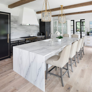 Kitchen - contemporary light wood floor and beige floor kitchen idea in Minneapolis with an undermount sink, black cabinets, marble countertops, white backsplash, marble backsplash, black appliances, an island and white countertops