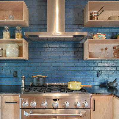 Mid-sized minimalist l-shaped medium tone wood floor and brown floor eat-in kitchen photo in San Francisco with flat-panel cabinets, light wood cabinets, granite countertops, blue backsplash, ceramic backsplash, stainless steel appliances, a peninsula and black countertops