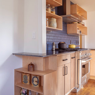 Design ideas for a mid-sized modern l-shaped eat-in kitchen in San Francisco with an undermount sink, flat-panel cabinets, light wood cabinets, granite benchtops, blue splashback, ceramic splashback, stainless steel appliances, medium hardwood floors, a peninsula, brown floor and black benchtop.