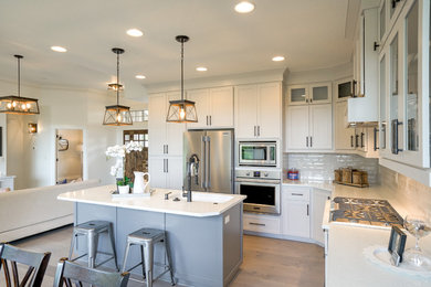 Example of a mid-sized transitional l-shaped brown floor and light wood floor open concept kitchen design in Portland with shaker cabinets, subway tile backsplash, stainless steel appliances, an island, an undermount sink, gray cabinets, white backsplash and white countertops