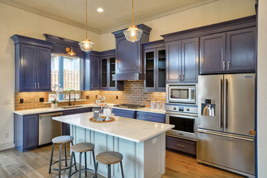 Kitchen - mid-sized transitional l-shaped medium tone wood floor and brown floor kitchen idea in Portland with an undermount sink, recessed-panel cabinets, blue cabinets, quartzite countertops, red backsplash, brick backsplash, stainless steel appliances, an island and white countertops