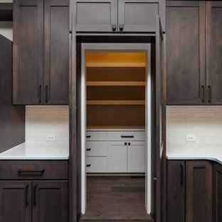 This is an example of a transitional u-shaped eat-in kitchen in Other with an undermount sink, shaker cabinets, medium wood cabinets, quartz benchtops, white splashback, ceramic splashback, stainless steel appliances, carpet, multiple islands, brown floor and white benchtop.