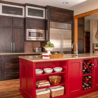 Immagine di una cucina chic con lavello sottopiano, ante in legno bruno, isola, pavimento marrone, top beige, ante in stile shaker, paraspruzzi marrone, paraspruzzi con piastrelle a listelli, elettrodomestici in acciaio inossidabile e parquet scuro