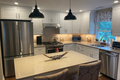 ニューヨークにある高級なトラディショナルスタイルのおしゃれなアイランドキッチン (白いキャビネット、シルバーの調理設備、無垢フローリング) の写真