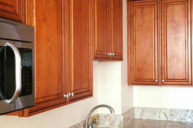 This is an example of a medium sized classic l-shaped kitchen/diner in New Orleans with raised-panel cabinets, medium wood cabinets, an island, a submerged sink, granite worktops, stainless steel appliances and medium hardwood flooring.