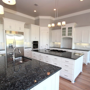 Large transitional eat-in kitchen ideas - Eat-in kitchen - large transitional u-shaped light wood floor eat-in kitchen idea in Dallas with an undermount sink, recessed-panel cabinets, white cabinets, granite countertops, white backsplash, stainless steel appliances and two islands