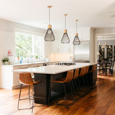 Inspiration for a large transitional u-shaped medium tone wood floor and brown floor open concept kitchen remodel in Seattle with shaker cabinets, white cabinets, quartz countertops, an island, white countertops, an undermount sink, white backsplash, subway tile backsplash and stainless steel appliances
