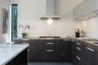 Example of a minimalist l-shaped gray floor kitchen design in San Francisco with flat-panel cabinets, gray cabinets, stainless steel countertops, white backsplash, glass sheet backsplash, stainless steel appliances and an island