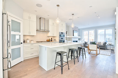 Example of an arts and crafts single-wall light wood floor and brown floor eat-in kitchen design in Calgary with an undermount sink, shaker cabinets, white cabinets, quartzite countertops, beige backsplash, ceramic backsplash, stainless steel appliances and an island
