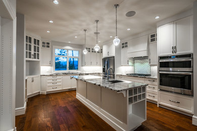 Example of a large transitional u-shaped dark wood floor and brown floor eat-in kitchen design in Other with an undermount sink, recessed-panel cabinets, white cabinets, granite countertops, white backsplash, ceramic backsplash, stainless steel appliances, an island and multicolored countertops