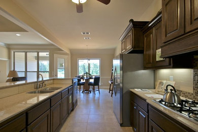Enclosed kitchen - mid-sized traditional galley ceramic tile and beige floor enclosed kitchen idea in New Orleans with raised-panel cabinets, medium tone wood cabinets, a peninsula, a double-bowl sink, quartz countertops, multicolored backsplash, mosaic tile backsplash and stainless steel appliances