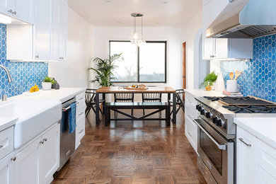 Transitional galley dark wood floor and brown floor eat-in kitchen photo in San Francisco with a farmhouse sink, shaker cabinets, white cabinets, blue backsplash, stainless steel appliances, no island and white countertops