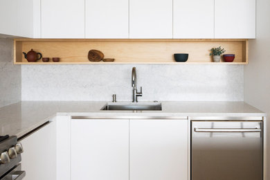 Eat-in kitchen - mid-sized modern l-shaped light wood floor and yellow floor eat-in kitchen idea in Chicago with an undermount sink, flat-panel cabinets, white cabinets, quartzite countertops, gray backsplash, stainless steel appliances, an island and gray countertops