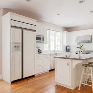 Large traditional kitchen pictures - Kitchen - large traditional l-shaped medium tone wood floor and orange floor kitchen idea in Boston with raised-panel cabinets, white cabinets, solid surface countertops, white backsplash, an island, white countertops, an undermount sink and paneled appliances