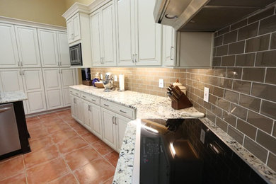 オーランドにあるおしゃれなキッチン (白いキャビネット、御影石カウンター、シルバーの調理設備、ベージュキッチンパネル) の写真