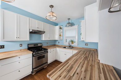 Design ideas for a traditional u-shaped kitchen/diner in DC Metro with a built-in sink, shaker cabinets, white cabinets, wood worktops, stainless steel appliances, medium hardwood flooring and a breakfast bar.