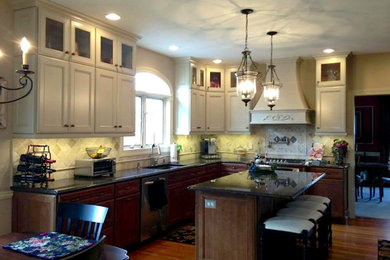 Example of a mid-sized transitional l-shaped medium tone wood floor and brown floor eat-in kitchen design in Philadelphia with an undermount sink, recessed-panel cabinets, white cabinets, granite countertops, beige backsplash, stone tile backsplash, stainless steel appliances and an island