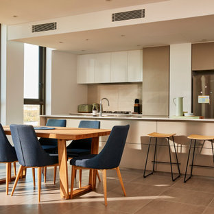 This is an example of a large contemporary galley eat-in kitchen in Sydney with an undermount sink, grey cabinets, quartz benchtops, white splashback, ceramic splashback, stainless steel appliances, ceramic floors, with island, white benchtop, flat-panel cabinets and brown floor.