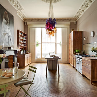 Inspiration for an eclectic galley eat-in kitchen in Other with flat-panel cabinets, medium wood cabinets, wood benchtops, white splashback, subway tile splashback, stainless steel appliances, medium hardwood floors, with island and brown floor.