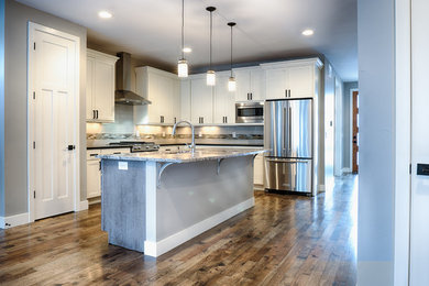 Eat-in kitchen - large modern l-shaped medium tone wood floor and brown floor eat-in kitchen idea in Denver with shaker cabinets, white cabinets, stainless steel appliances, an island, an undermount sink, granite countertops, white backsplash and subway tile backsplash