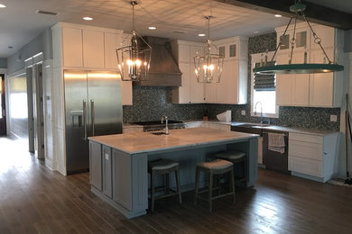 Example of a large beach style l-shaped medium tone wood floor and brown floor eat-in kitchen design in Miami with a farmhouse sink, shaker cabinets, white cabinets, marble countertops, blue backsplash, mosaic tile backsplash, stainless steel appliances and an island