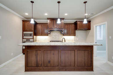Example of a large classic single-wall porcelain tile eat-in kitchen design in Austin with an undermount sink, raised-panel cabinets, brown cabinets, granite countertops, beige backsplash, stone tile backsplash, stainless steel appliances and an island