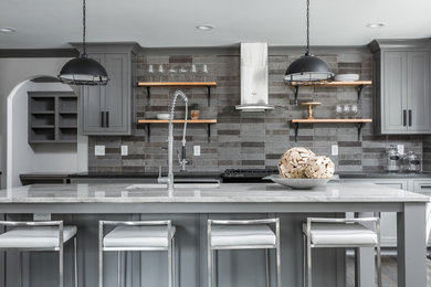 Große Wohnküche mit grauen Schränken, Küchenrückwand in Grau, Küchengeräten aus Edelstahl und Kücheninsel in Indianapolis