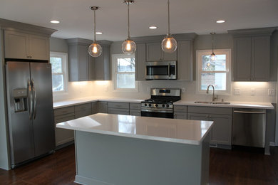 Example of a transitional l-shaped dark wood floor and brown floor eat-in kitchen design in Minneapolis with an undermount sink, shaker cabinets, gray cabinets, quartzite countertops, white backsplash, ceramic backsplash, stainless steel appliances and an island