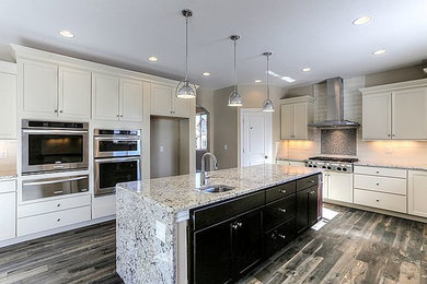 Medium tone wood floor open concept kitchen photo in Denver with flat-panel cabinets, white cabinets, granite countertops, white backsplash, ceramic backsplash, stainless steel appliances and an island
