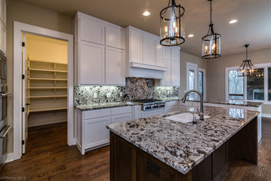 Example of a large transitional u-shaped medium tone wood floor kitchen design in Other with an undermount sink, shaker cabinets, white cabinets, granite countertops, multicolored backsplash, stone slab backsplash, stainless steel appliances and an island