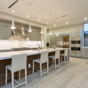 Kitchen - contemporary l-shaped light wood floor kitchen idea in Austin with an undermount sink, flat-panel cabinets, gray cabinets, white backsplash, stainless steel appliances and an island