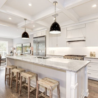 Inspiration for a mid-sized transitional galley medium tone wood floor and brown floor open concept kitchen remodel in DC Metro with an undermount sink, shaker cabinets, white cabinets, granite countertops, white backsplash, ceramic backsplash, stainless steel appliances, an island and beige countertops