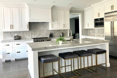 Mid-sized transitional l-shaped dark wood floor and brown floor eat-in kitchen photo with a double-bowl sink, shaker cabinets, white cabinets, quartzite countertops, beige backsplash, stone slab backsplash, stainless steel appliances, an island and beige countertops