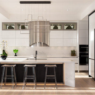 Inspiration for a contemporary l-shaped kitchen in Toronto with an undermount sink, flat-panel cabinets, white cabinets, white splashback, white appliances, light hardwood floors, with island, beige floor, white benchtop and recessed.