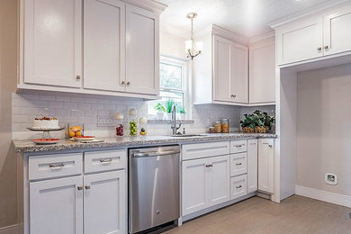 Example of a mid-sized arts and crafts galley vinyl floor and beige floor open concept kitchen design in Houston with a single-bowl sink, shaker cabinets, white cabinets, granite countertops, white backsplash, subway tile backsplash, stainless steel appliances and no island